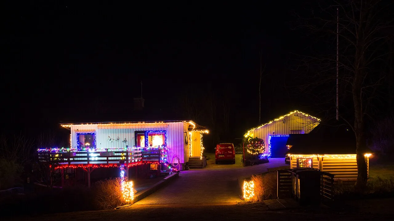 Two houses at night with warm white lights along the rooflines and porch railings